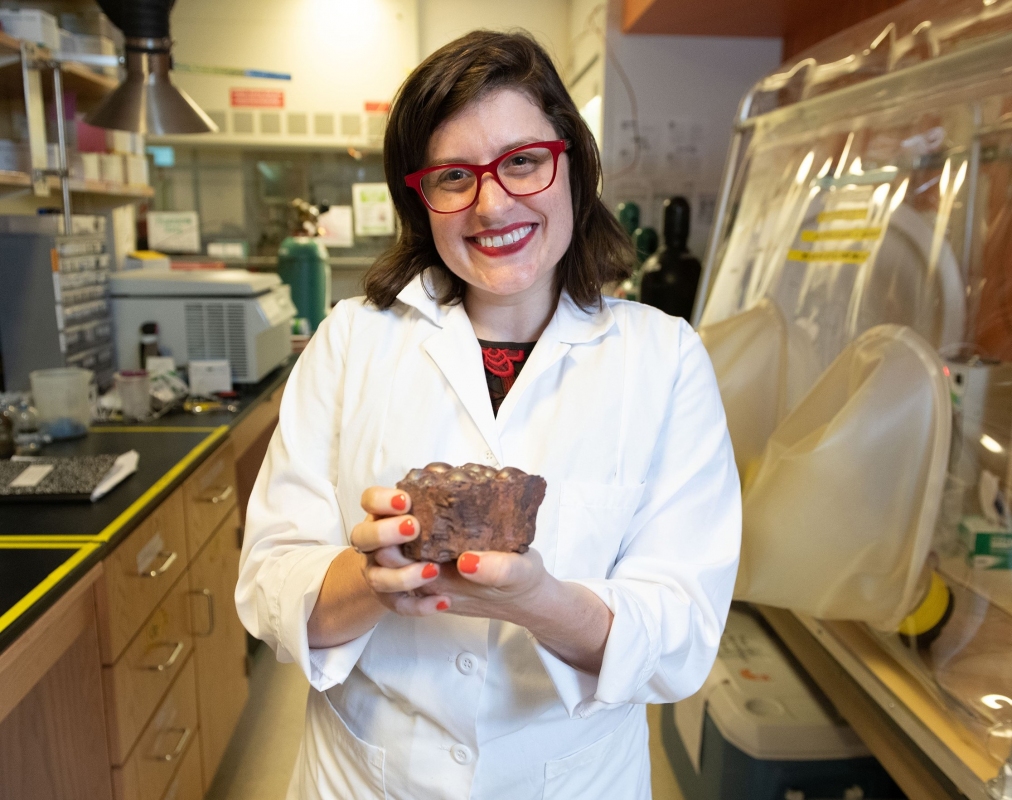 jen glass holding material in her hand in a lab